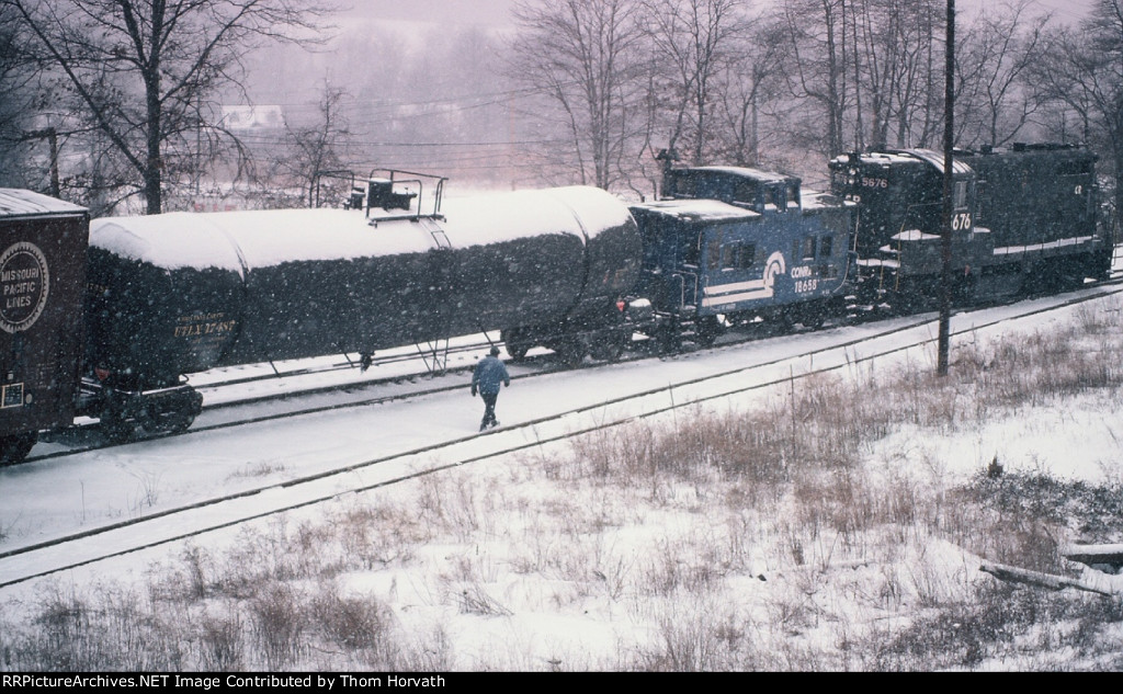 The conductor walks back to the a warm cab and will head west with his train 